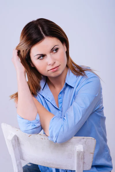 Donna in camicia blu seduta sulla sedia — Foto Stock