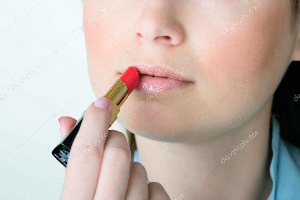 portrait of young woman applying lips make up