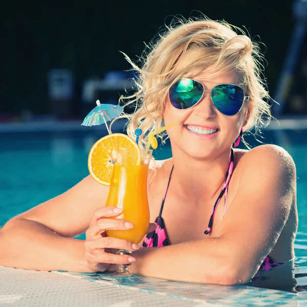 Menina com suco de laranja fresco na piscina de luxo — Fotografia de Stock