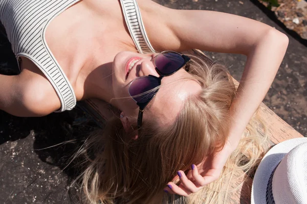 Allongé blonde souriant femme modèle portant des lunettes de soleil sur vieux stad — Photo