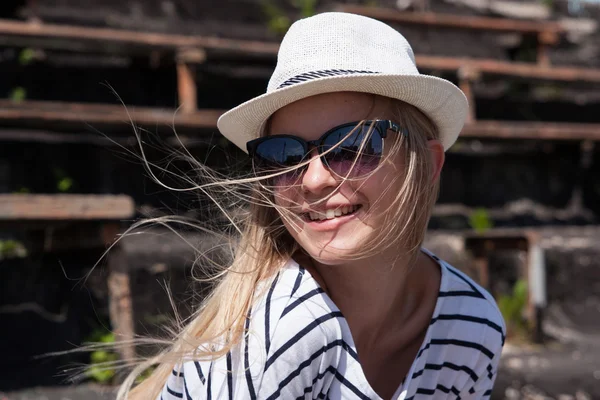 Modèle femme blonde souriante portant des lunettes de soleil et un chapeau devant — Photo