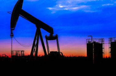 Petrol sahası günbatımı gökyüzü arka plan ile yağ pompaları silüeti