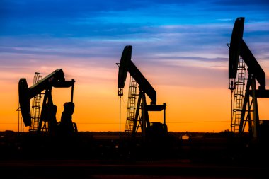 Petrol sahası günbatımı gökyüzü arka plan ile yağ pompaları silüeti