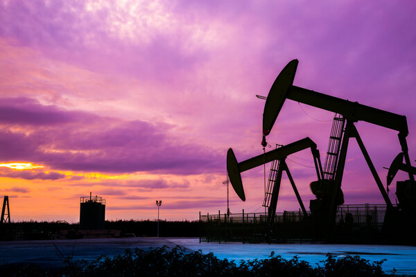 Silhouette of Oil pumps at oil field with sunset sky background