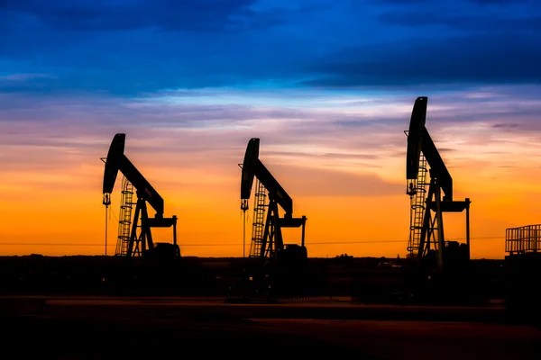 Silueta de bombas de aceite en el campo petrolífero con fondo cielo puesta del sol — Foto de Stock