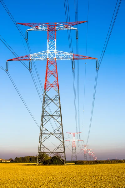 Electricity transmission pylon silhouetted against blue — Stock Photo, Image