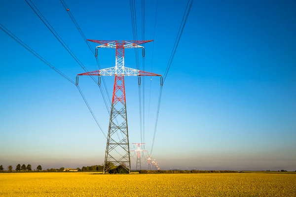 Electricity transmission pylon silhouetted against blue — Stock Photo, Image