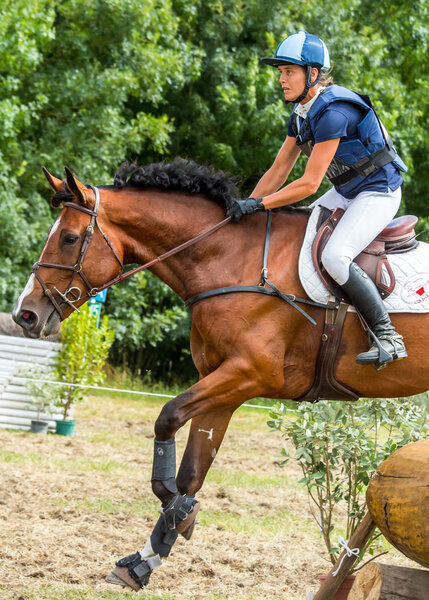 Saint Cyr du Doret, France - July 29, 2016: Horseman riding horse over an obstacle on cross country event