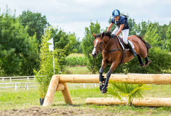 Saint Cyr du Doret, France - July 29, 2016: Woman riding horse over obstacle on cross country event