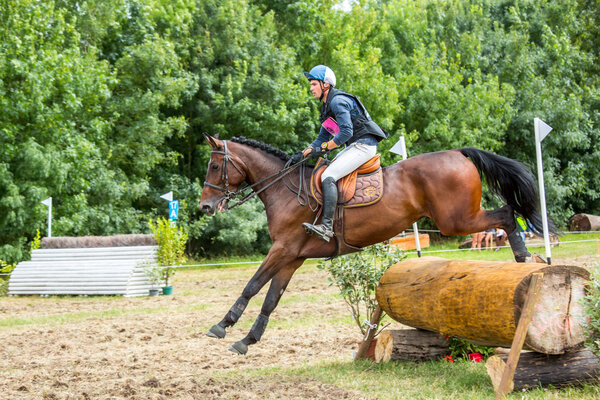 Saint Cyr du Doret, France - July 29, 2016: Horseman riding horse over an obstacle on cross country event