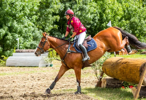 Saint Cyr du Doret, Francia - 29 de julio de 2016: Mujer montando a caballo sobre un obstáculo en un evento a campo traviesa — Foto de Stock