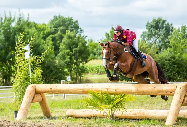 Saint Cyr du Doret, Francia - 29 de julio de 2016: Mujer montando a caballo sobre un obstáculo en un evento a campo traviesa — Foto de Stock