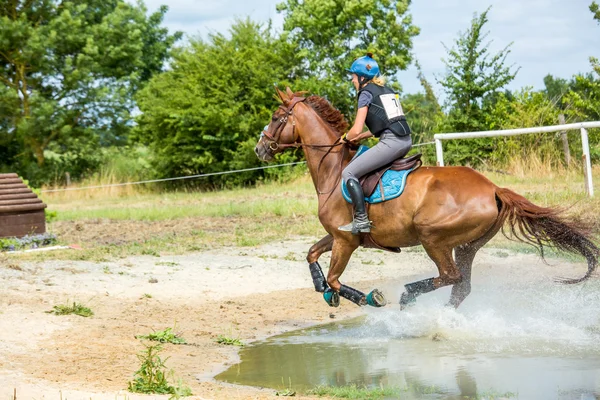 Saint Cyr du Doret, Francia - 29 de julio de 2016: Jinete que cruza el salto de agua galopando en una manisfestación a campo traviesa — Foto de Stock