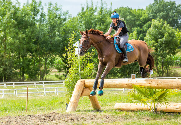 Saint Cyr du Doret, France - July 29, 2016: Woman riding horse over obstacle on cross country event