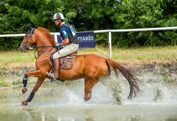 Saint Cyr du Doret, France - July 29, 2016: Rider crossing water jump galloping at a cross country manisfestation — Stock Photo, Image