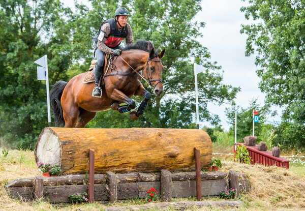 Saint Cyr du Doret, France - July 29, 2016: Horseman riding horse over an obstacle on cross country event