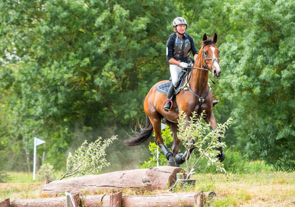 Saint Cyr du Doret, France - July 29, 2016: Rider on her galloping horse during a cross country manisfestation