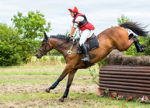 Saint Cyr du Doret, France - July 29, 2016: Woman riding horse over obstacle on cross country event