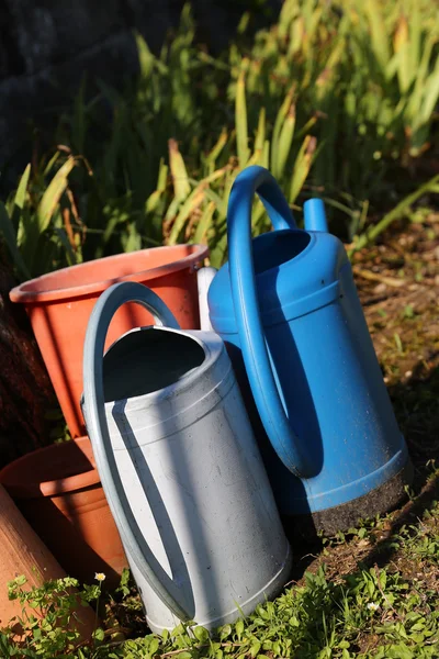 Two colorful watering pots splaced in the middle of the garden — Stock Photo, Image