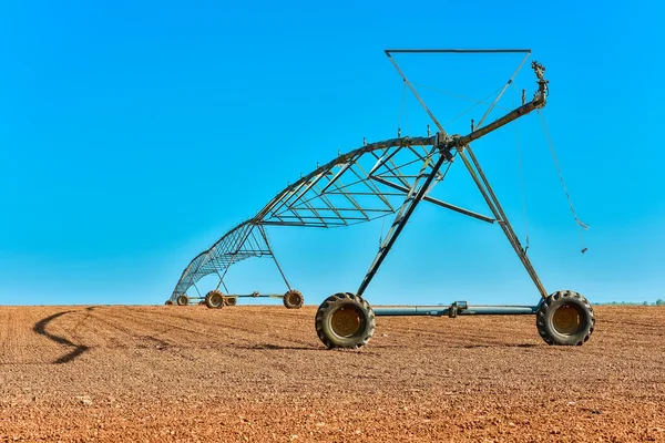 A big farming sprinkler out in the middle of wide field — Stock Photo, Image