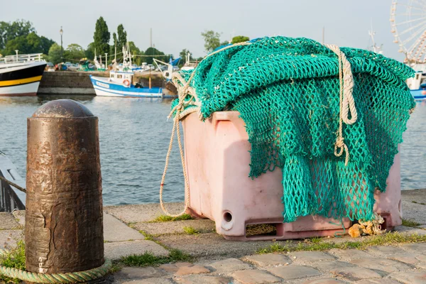 A big pile of fishing net in the harbor with ships and merry-go-round in the backgrouond — Stock Photo, Image