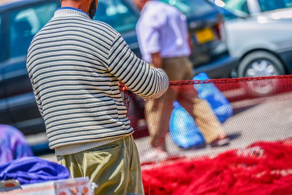 Sailor repairing the red fishing net — Stock Photo, Image