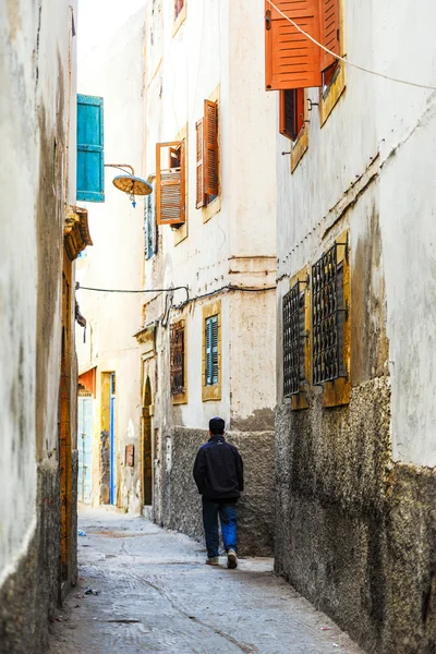 A man walking along an empty narrow street — Stock Photo, Image