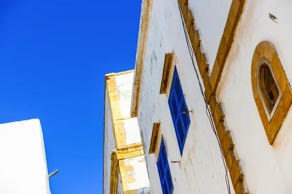 Witte muur met blauwe windows en gele kaders — Stockfoto