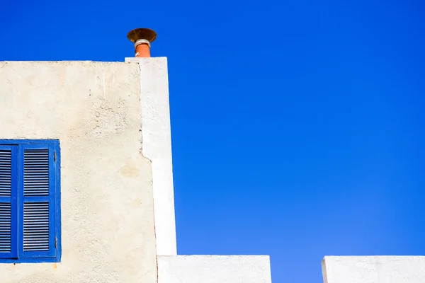 Un pedazo de ventana azul en un pedazo de pared blanca en el pedazo de cielo azul — Foto de Stock