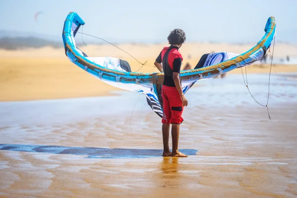 一名年轻男子拿着一个面朝大海的冲浪风筝 — 图库照片
