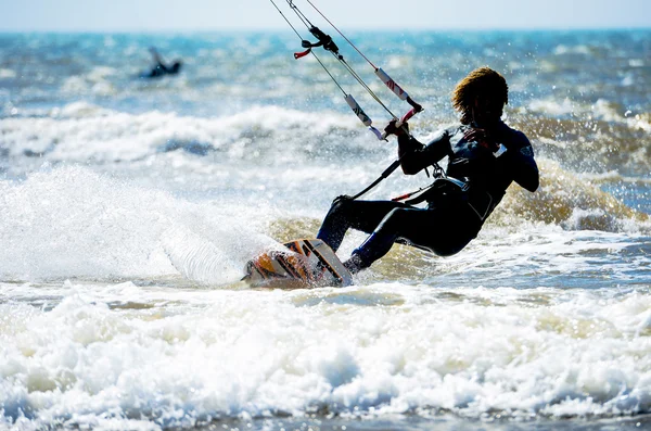 Um jovem desportivo kitesurf nas ondas — Fotografia de Stock