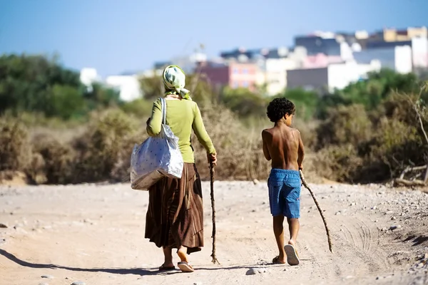 Uma mulher idosa e um menino caminhando em direção à cidade — Fotografia de Stock