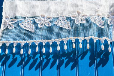 white lace curtains on a blue wooden shutter clipart