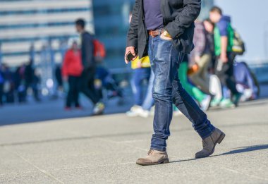 Yoğun bir cadde üzerinde yürüyen bir gencin bacakları
