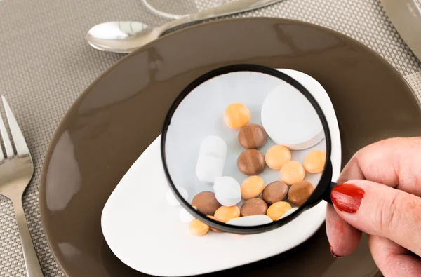 Observeren kleurrijke pillen door vergrootglas — Stockfoto