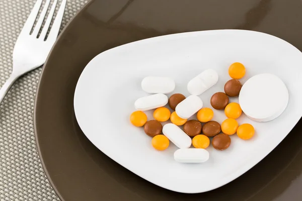 Closeup to a plate with pills with a fork to one side — Stock Photo, Image
