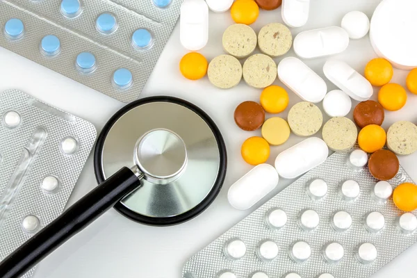 Stethoscope in the middle of pile of pills and blister packs — Stock Photo, Image