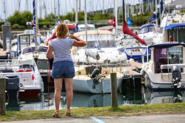 Une dame en chemise rayée regardant port occupé avec de nombreux navires — Photo