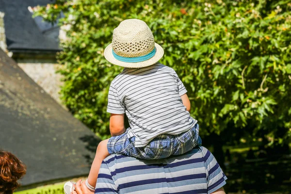 Мальчик в соломенной шляпе сидит на плечах своего отца в парке — стоковое фото