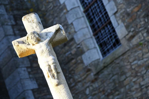 Closeup to stone cross statue in front of an old building — Stock Photo, Image