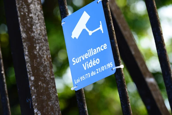 Blauw bord van videobewaking vastgemaakt aan metalen hek — Stockfoto