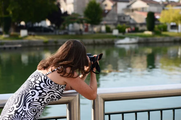 Female photographer leaning over the bridge railing to take a ph — Stock Photo, Image