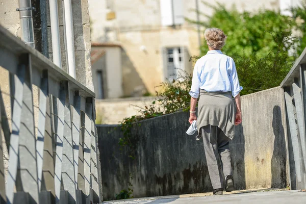 Una donna anziana che cammina lungo uno stretto passaggio — Foto Stock