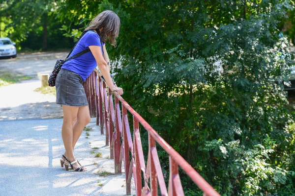 Young woman leaning on red metallic railing — Stock Photo, Image