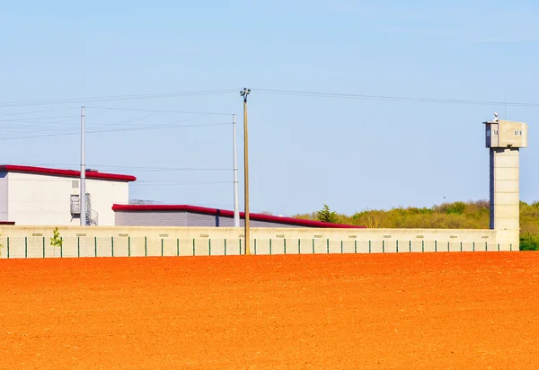 Prison area with a tall watchtower surrounded with fence — Stock Photo, Image