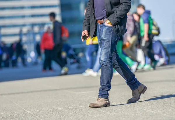 Legs of a young person walking on a busy street — Stock Photo, Image