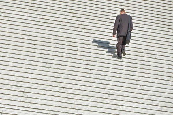 Een man langs grote eindeloze trap klimmen — Stockfoto