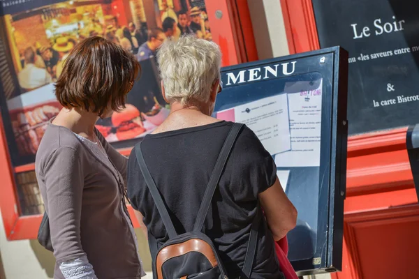 Two women checking the menu at the entrance to a restaurante — Stock Photo, Image