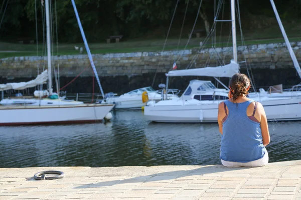 A young woman sitting at the harbor and talking on her phone — Stock Photo, Image