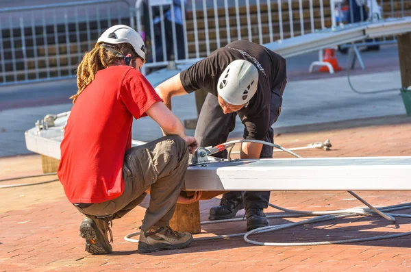 Twee werknemers in de bouw bevestiging metalen stuk over houten log — Stockfoto